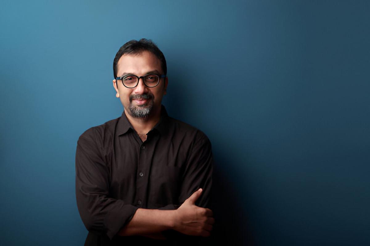 a man with glasses standing in front of a blue wall